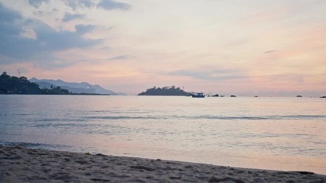 Calm tropical beach at sunrise with distant boat