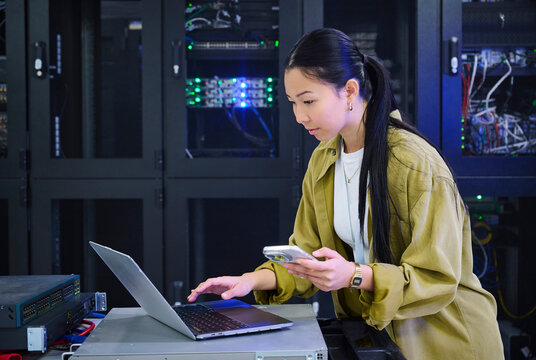 Female IT Professional working on Laptop in Server Room