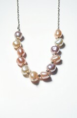 Fototapeta premium Multi colored pearls and silver chain necklace isolated on white background. Luxury jewelry for women, elegant fashion accessory for special occasions.