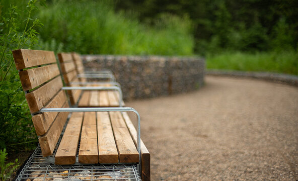 Close-up of a new wooden park bench with a very softly focused background
