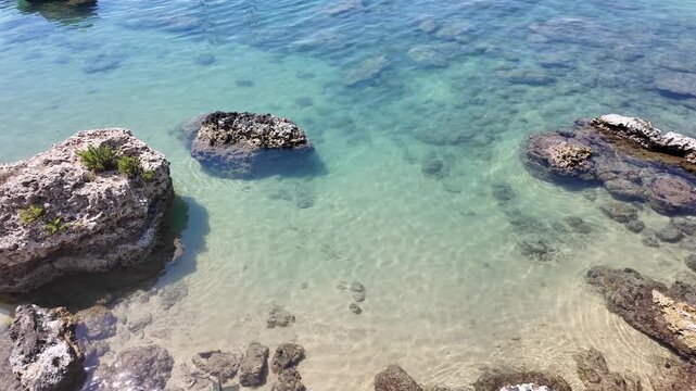 Rock formations in shallow water no action observed static scene, in beach or coastal area with clear shallow waters, with rock formations, clear blue water, sand, with rocks, water, sand texture.