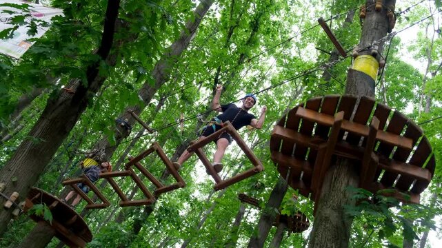 Man and boy navigating high ropes course with swinging wooden frames