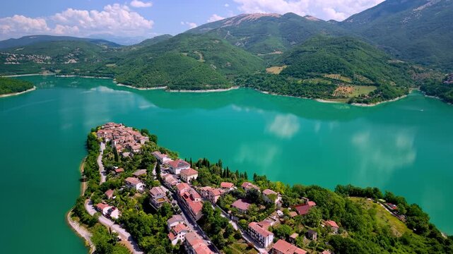 Colle di Tora Lake Turano Lazio Italy Aerial Drone Cinematic Panning Reveal over Picturesque Peninsula Village with Calm Turquoise Water and Green Mountain Scenery Travel Video 4K UHD