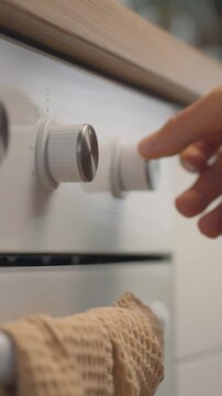 An amateur cook turns the oven dial in a modern kitchen, setting the temperature precisely and engaging the baking function with broad hand movements as part of the baking setup process