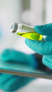 Close-up of a doctor's gloved hands holding several medicine bottles, comparing drug labels, while an anesthesiologist reviews the data to choose the appropriate medicinal fluid for patient care