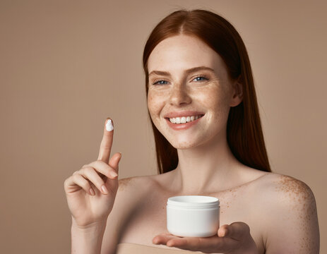 Smiling Redhead Woman with Freckles Holding White Cosmetic Cream Jar
