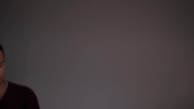 Young frightened man with sweaty face feeling scared and desperate in dark, confined space. Body jolts with sudden impulse, then pushes away from imaginary wall and steps back.
