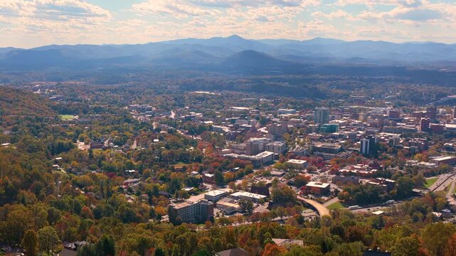Asheville, North Carolina during fall season with colorful forests surrounding downtown skyline. Scenic Appalachian landscape creates beautiful travel destination.