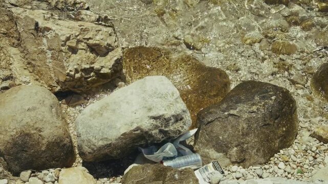 Plastic Garbage And Aluminum Can Litter Discarded Among Rocks On Stony Sea Beach. Environmental Pollution