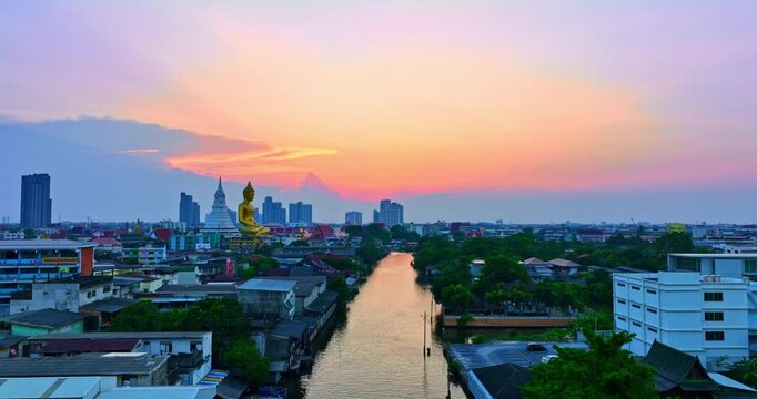 A striking aerial view of Bangkok featuring a golden Buddha statue and a white stupa surrounded by colorful temple rooftops, set against the backdrop of the modern city skyline.