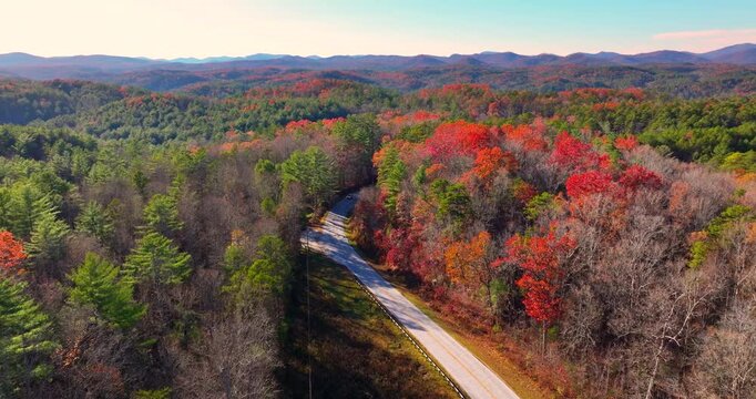Blue Ridge Parkway at sunset in autumn. Scenic route between majestic mountain hills covered in golden and scarlet leaves.