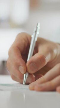 Pharmacist wearing white coat signs doctor's prescription with pen at pharmaceutical service counter, carefully recording the paper document to ensure compliance with pharmacy dispensing regulations