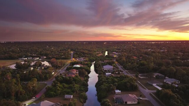 Flood water canal in residential area in North Port, Florida with private homes, tropical landscape and bright evening atmosphere. Real estate in American South.