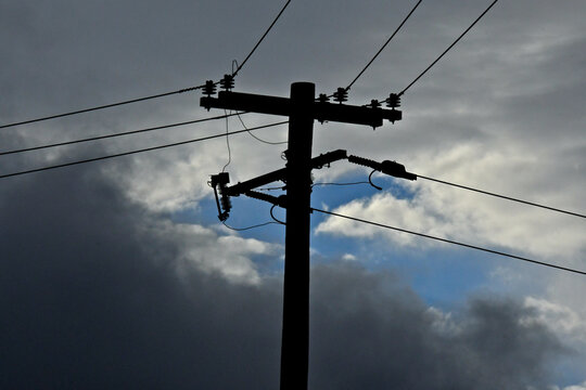 Silhouette of retrofitted old power pole with dropout fuses 