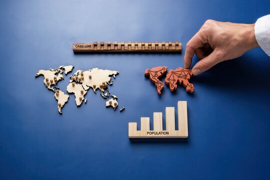 A hand places a wooden puzzle piece of Africa on a world map alongside a ruler and bar graph on a blue surface.