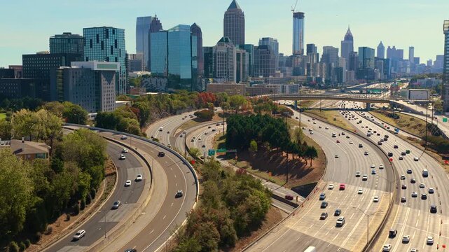 Rush hour highway traffic driving past Atlanta city landscape with tall skyscraper buildings. Fast urban rhythm, daily commute and metropolitan lifestyle.