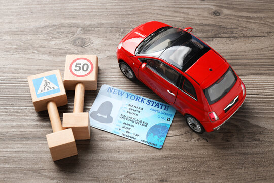 Driver's licence, car model and mini traffic signs on wooden background