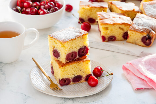 Delicious cherry pie or cake squares with powdered sugar on a marble background. Selective focus