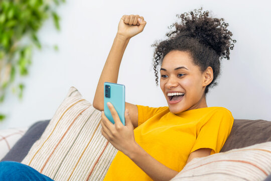 Black Woman Celebrating Smartphone Success At Home