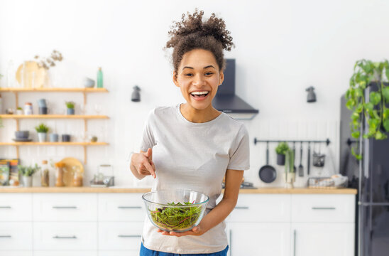 Happy black woman pointing at healthy salad