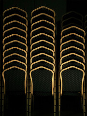 Vertical Columns of Stacked Banquet Chairs in Low Light - Event Venue Storage and Furniture Management Pattern © Pola_Creative