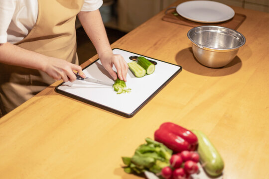 Person cutting fresh cucumber on kitchen counter for healthy mea