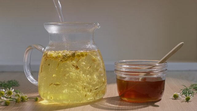 Pouring Chamomile Flowers Into A Glass Teapot For Brewing Aromatic And Healthy Herbal Tea