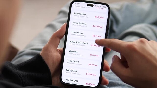 Close-up of a person scrolling through mobile plan options in a telecom app. From 5G speed to global roaming and cloud storage. Perfect for videos about mobile technology, digital lifestyle, and