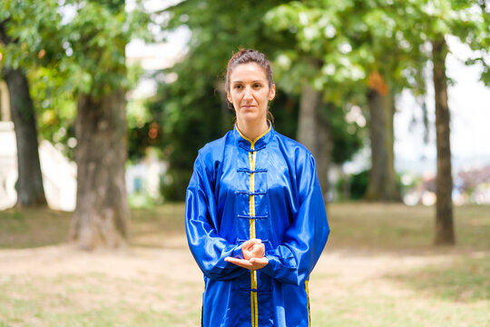 Woman practicing tai chi in blue uniform outdoors