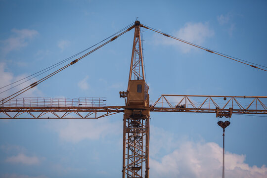 Close-up of a yellow tower crane jib end against clear blue sky with large copy space