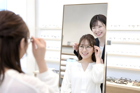 メガネ店で眼鏡を試着する客と店員