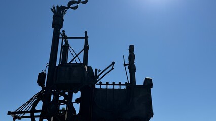 Vintage Steam Engine Sculpture: A striking silhouette of a vintage steam engine sculpture against a clear blue sky, exuding a sense of industrial heritage and mechanical wonder. © Maria