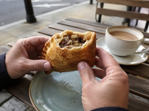 Disfrutar de un bollo con carne y un caf&eacute; en la calle durante una ma&ntilde;ana