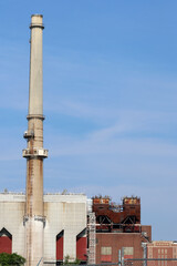 Fototapeta premium Industrial Factory with Smokestack and Manufacturing Buildings Under Blue Sky