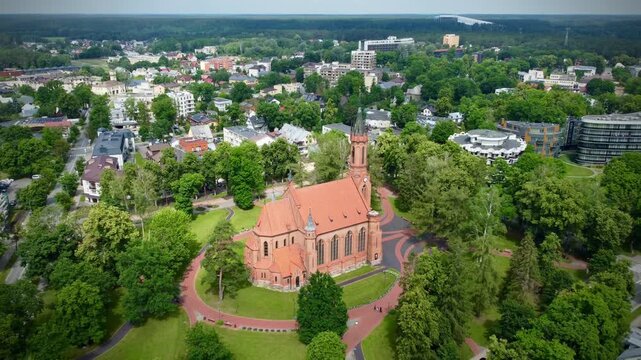 Church of Saint Mary's Scapular, located in Druskininkai, Lithuania, exhibits Gothic Revival architecture with its striking red brick facade and tall, narrow windows.