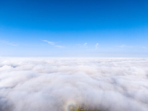 Aerial view of a sea of clouds under a clear blue sky with a faint glory phenomenon visible in Weingarten, Baden-Wurttemberg, Germany.