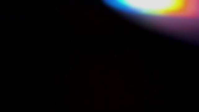 Abstract video of intermittent chromatic light leaks with a bright white core appearing from the right side over a black background, leaving copy space on the left for titles, overlays and transitions