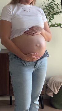 UGC-style vertical phone video of a pregnant woman cradling her bare baby bump at home, an authentic candid symbol of anticipation and motherhood