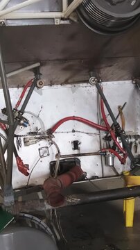 Empty helicopter engine compartment in maintenance hangar, missing powerplant revealing internal mounting structures and avionics components during repair work