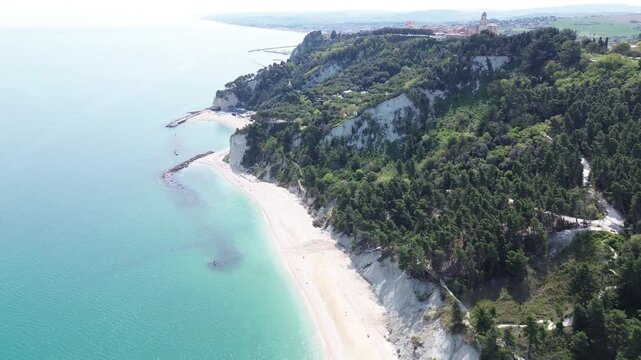Sirolo, Riviera del Conero, Marche, Italy. Aerial drone footage of white cliffs, turquoise Adriatic Sea, sandy beach and coastal village on a sunny summer day.