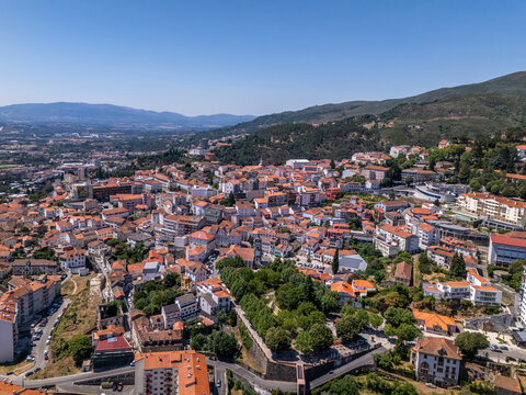 Aerial view of the historic town of Covilha with its dense cluster of terracotta-roofed buildings and surrounding green hills in Covilha, Castelo Branco District, Portugal.