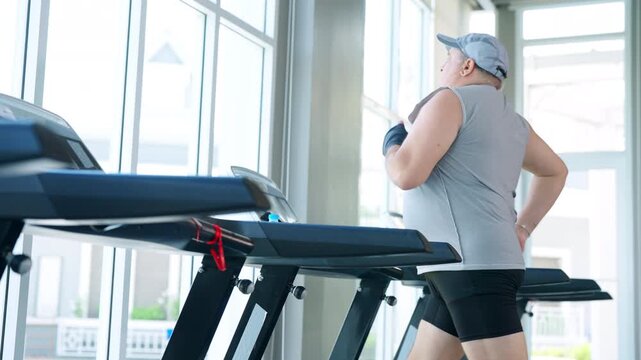 Mature overweight man running workout on treadmill at fitness gym to improve health through cardio exercise weight loss endurance healthy active lifestyle fitness sport training healthy aging wellness