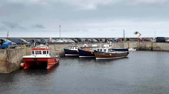 Seahouses harbour, boats moored, pull back shot revealing wider quay, calm water, fishing village on the North East coast, coastal scenery expanding into the harbour.