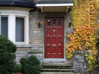 Fototapeta premium front door of old stone house covered in ivy with fall colors