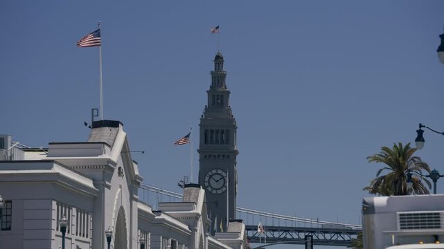Old Ferry Building Clock Tower With American Flags Over Clear Sky In San Francisco