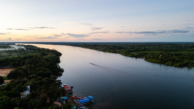 Dramatic golden sunset fading over the endless forest horizon, bathing the Ucayali River waters in warm yellow light.