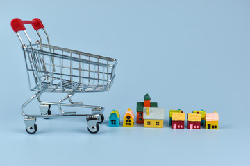 Mini shopping cart with red handles stands on blue surface © Nazir