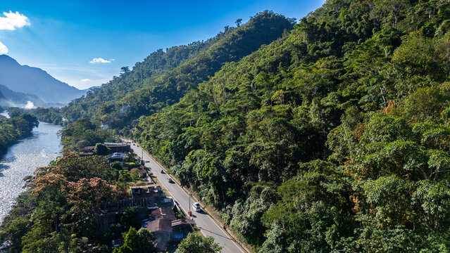 Lush emerald mountains of the Peruvian cloud forest of Tingo Maria framing a remote asphalt highway from a bird's eye view.