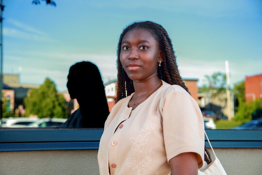 Urban portrait of a confident young Black woman standing in front of a modern glass building