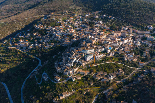 Aerial view of the historic town of Capestrano with its dense stone buildings, narrow streets, and surrounding hills in Capestrano, Abruzzo, Italy.